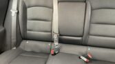 Black fabric car rear seat with three seat belts and a fold-down center armrest visible in the middle.