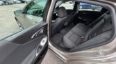 Open rear passenger door reveals the gray SUV interior with black cloth seats and center console, parked in a lot with other cars visible outside the door.