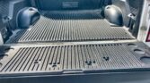 Empty pickup truck bed with a ribbed plastic liner and curved wheel wells on both sides, tailgate down