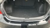 Open trunk in a black sedan showing a dark, empty cargo area with the rear seats upright and carpet lining.