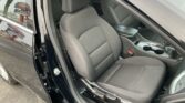 Front passenger area of a dark gray car with fabric seats, center console, and cup holders visible through an open door.