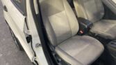 Left-side car door open revealing the two front seats and center console inside a light-colored sedan interior.