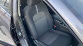 Front driver’s seat in a dark fabric car interior, door open and headrest visible.