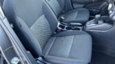 Front interior of a car showing black cloth seats with patterned center panels, gear shifter, and cup holders.