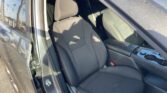 Interior of a car showing the front seats in dark fabric with white stitching and the open front-left door.