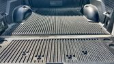 Black pickup truck bed with a ribbed bed liner, wheel wells on each side, and a TrailFX logo on the back wall.