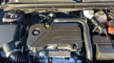 Under-hood view of a car engine with an ECOTEC engine cover and visible coolant reservoir hoses and components.