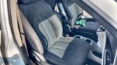 Front interior of a car showing black fabric seats with white stitching, center console, and a green cloth on the passenger seat.
