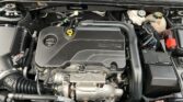 Close-up of car engine bay showing ECOTEC engine cover, coolant reservoir, and various hoses and wires.
