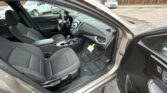 Open car door reveals a clean modern sedan interior with gray fabric seats, center console, and steering wheel view.