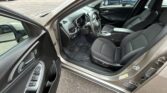 Open driver-side car door reveals black cloth front seats, steering wheel, and center console inside a Chevrolet vehicle in a parking lot.