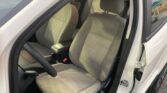 Driver-side car door is open, showing the gray fabric front seats and steering wheel inside a white vehicle.