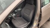Interior view of a car with the driver's seat and center console visible, gray fabric upholstery, and a raindrop-covered window outside.