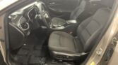 Interior view of a car's front seats and dashboard with the driver's door open, showing the steering wheel and center console in black upholstery