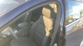 Open car door revealing gray fabric front seats and interior console in a parked car