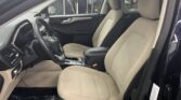 Interior of a car showing beige front seats, steering wheel, and center console from the driver's side door.