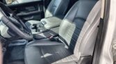 Front interior of a vehicle showing black leather driver and passenger seats, center console, and cup holders from the open driver door.