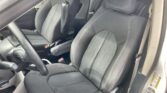 Front interior of a car showing black fabric seats with white stitching and a steering wheel.