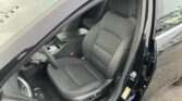 Interior view of a black sedan: driver seat and center console with door open, front passenger seat visible