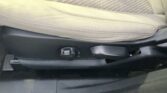 Beige car seat bottom with a black manual adjustment lever on the side and plastic trim beneath.