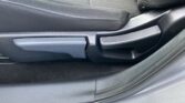 Car seat bottom with two side adjustment levers, black fabric upholstery and visible white stitching.