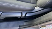 Close-up of a car seat edge in dark fabric with white stitching and an SRS AIRBAG label on the side panel, plus a tire/loading sticker nearby.