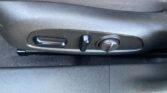 Side view of a car seat adjustment panel with a horizontal lever and a round knob on the lower edge of the seat base, used to change seating position.