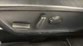 Close-up of a car's lower driver-side panel with a rectangular switch and a round knob/buttons nearby