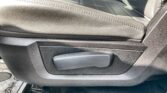 Driver's seat adjustment lever on a textured black leather car seat with visible stitching far-area trim.