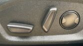 Close-up of a textured black car dashboard showing two rectangular switches and a round dial in the panel.