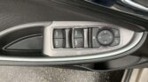 Driver-side car door panel featuring window control buttons and a circular mirror adjustment pad