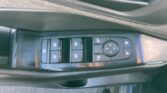 Close-up of a car door panel showing power window switches and round mirror control pad on the driver's side door