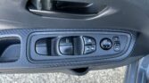 Driver-side car door interior with window and mirror controls on a textured panel (carbon-fiber look).