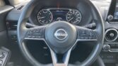 Dashboard view from the driver’s seat showing steering wheel with Nissan emblem, instrument cluster, and infotainment screen. (informative)