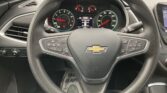 Steering wheel with Chevrolet emblem, dashboard gauges visible behind, including tachometer and speedometer, touch screen on right.
