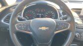 Steering wheel with Chevrolet emblem seen from the driver's seat, dashboard gauges ahead and an inset infotainment screen to the right.