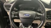 Steering wheel in a Ford car with integrated left and right control buttons and an empty instrument cluster behind it.