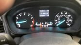 Close-up of a car's instrument cluster showing a central digital trip odometer readout, gear indicator (P R N D S), and circular speedometer and tachometer gauges on either side.