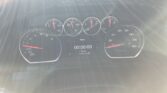 Vehicle instrument cluster with tachometer, speedometer, and center timer reading 00:00:00, with sun glare across the windshield.