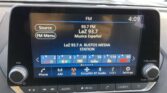 In-car infotainment screen showing FM radio at 93.7 LaZ Musica Español station