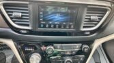 Center console with a touchscreen infotainment display showing radio, flanked by rectangular air vents and surrounding climate controls and knobs.