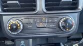 Car climate control panel with two horizontal air vents above and circular temperature/fan dials below, plus Auto and A/C buttons on a dark dashboard.