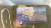 In-dash display showing the car's rear-view camera with orange parking guide lines over a parking lot scene