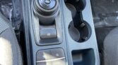 Center console with a circular gear selector showing R N D P L, cups to the right, and an electronic parking brake nearby.