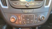 Car climate/infotainment console with buttons for home, back, power, and media controls above a center dial; visible display at top edge.