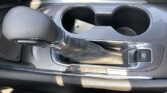 Center console of a car with two cup holders, gear selector showing P R N D, and an electronic parking brake button.