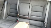 Rear car seat with three seating positions and three seat belts in dark gray fabric.