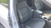 Open car door shows dark fabric front seats and center console with cupholders visible between them.