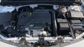 Front view of a car's engine bay with an ECOTEC engine cover, wiring, and hoses visible; battery and coolant reservoir on the right side.