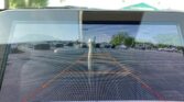 Rear-view camera display showing a parking lot with orange guide lines and surrounding cars.